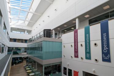 Flags hanging in our atrium showcasing our values, reading "Collaboration, Innovation and Openness"