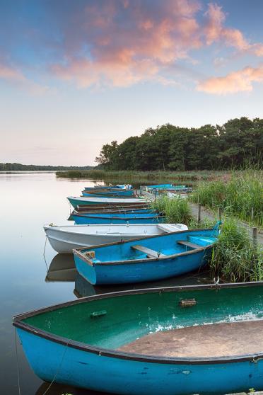 Boats moored to an old wooden jetty at Filby Broad on the Norfolk Broads near Great Yarmouth