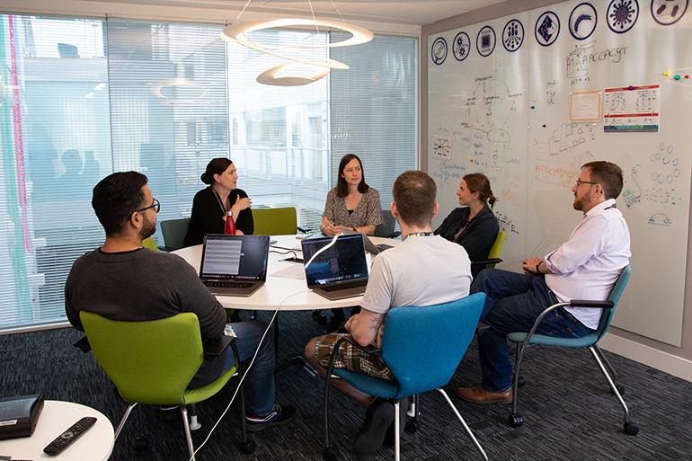 Colleagues from the Neil Hall Group sitting around a meeting table as part of their weekly group meeting.