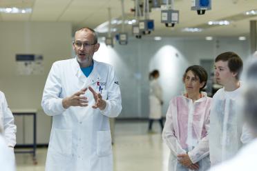 Dr Darren Heavens in the Genomics Pipelines labs at the Earlham Institute. Darren, wearing a white lab coat, is explaining our sequencing technologies to some members of the public on our last Open Day.