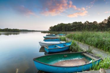 Boats moored to an old wooden jetty at Filby Broad on the Norfolk Broads near Great Yarmouth