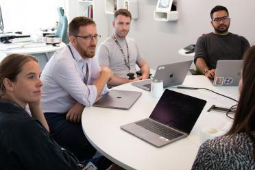 Colleagues from the Neil Hall Group sitting around a meeting table as part of their weekly group meeting.