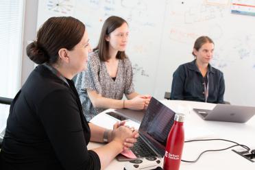 Hélène Yvanne with colleagues either side of her at a lab meeting with her group.