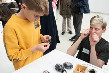 Public Engagement Officer Sam Rowe explaining the Darwin Tree of Life exhibition activities to a young child