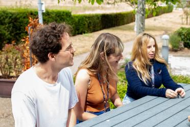 Students from the Earlham Institute Student Body sitting outside round a picnic bench in the summer.