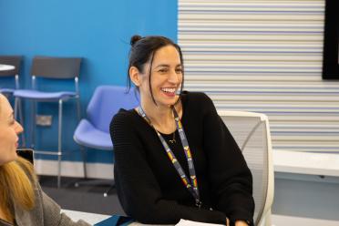 Dr Siobhan Dorai-Raj smiling and chatting with colleagues at a table