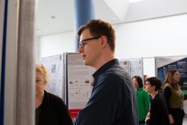 PhD researcher Charles Dickinson presenting his research poster at a symposium