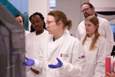 Research Assistant Vanda Knitlhoffer in the labs with a group of scientists explaining single-cell methodology