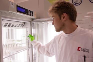 Visiting student reaching into a refrigerated unit with trays inside