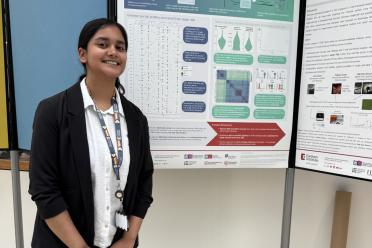 Diya standing in front of a research poster at the Earlham Institute