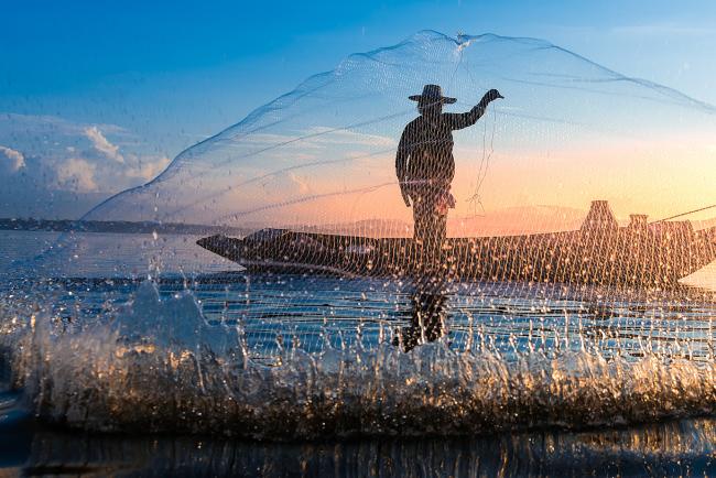 Photo shot of water spatter from fisherman while throwing fishing net on the lake.