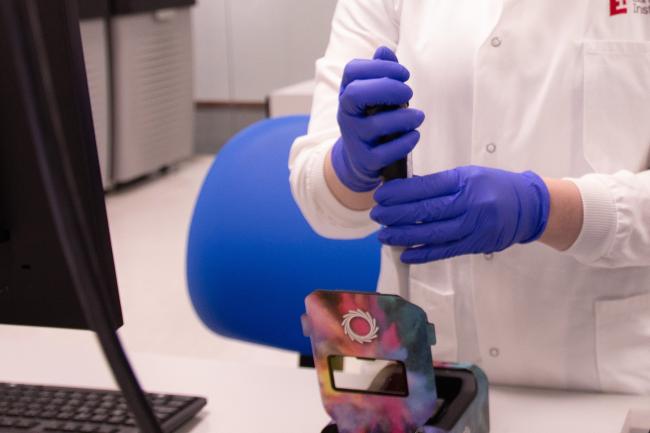 Scientist wearing blue protective gloves uses the ONT Promethion 2 Solo sequencer